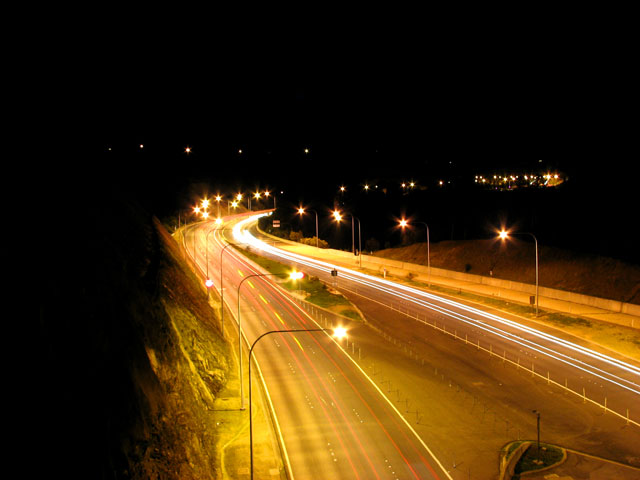 A long exposure view of the South Eastern Freeway at night. Bright headlights of vehicles show as long stripes across the image.